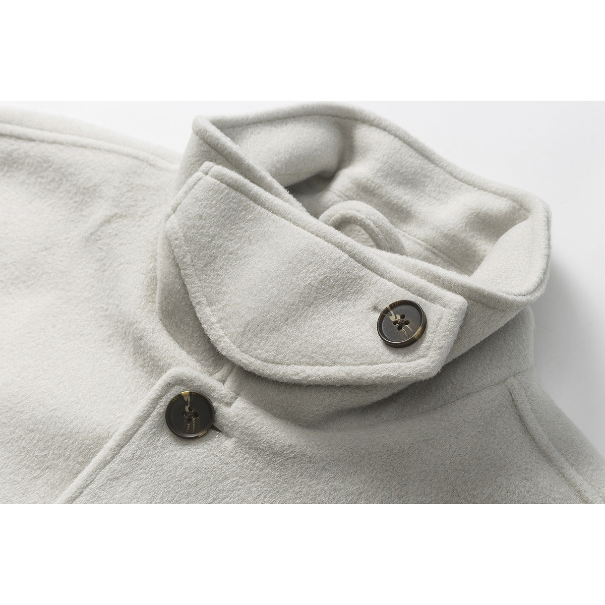 Close-up of an ivory coat’s oversized folded collar and dark buttons.