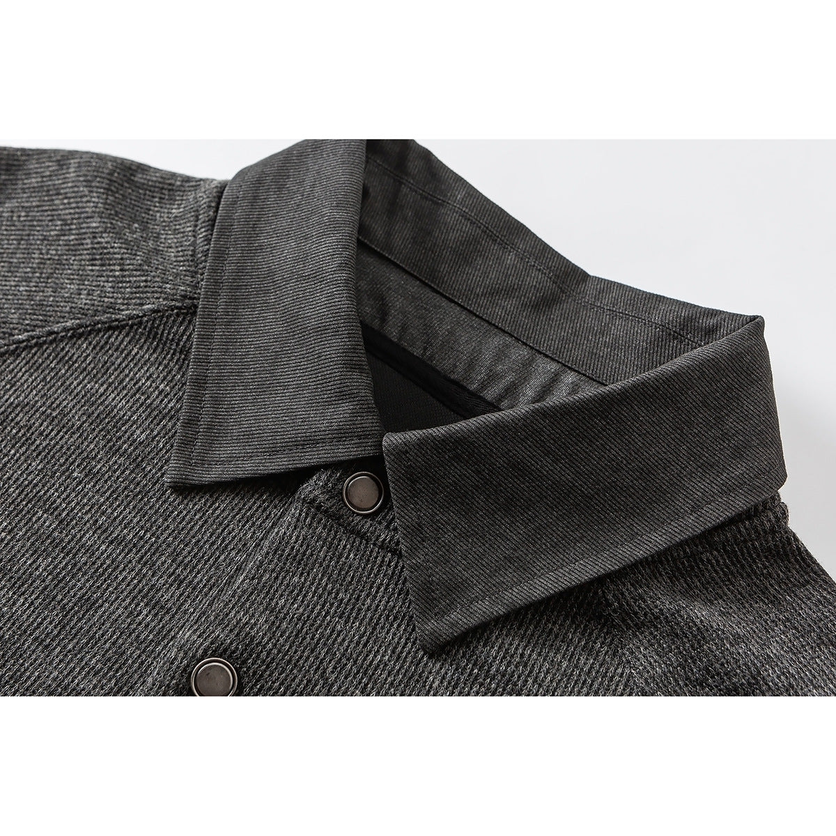 Close-up of a charcoal knit pullover's pointed collar and snap-button placket.