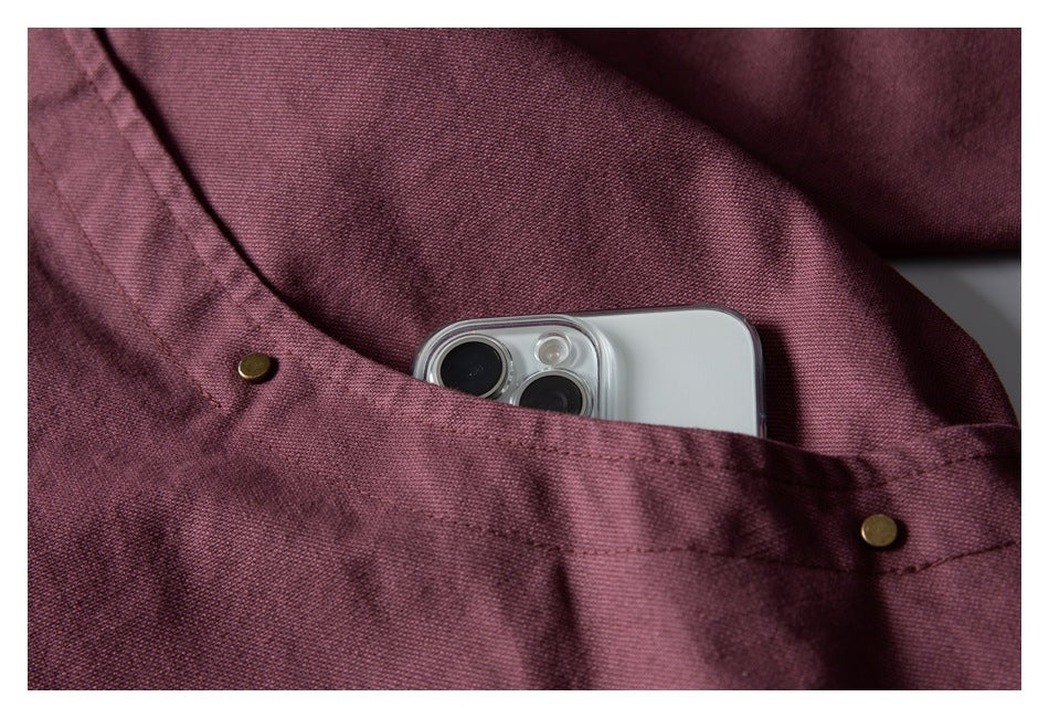 Close-up of a mauve jacket pocket with brass rivets, holding a silver smartphone.