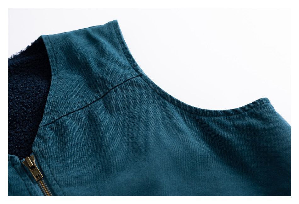 Close-up of a teal garment showing its neckline, dark fleece lining, and brass-tone zipper.