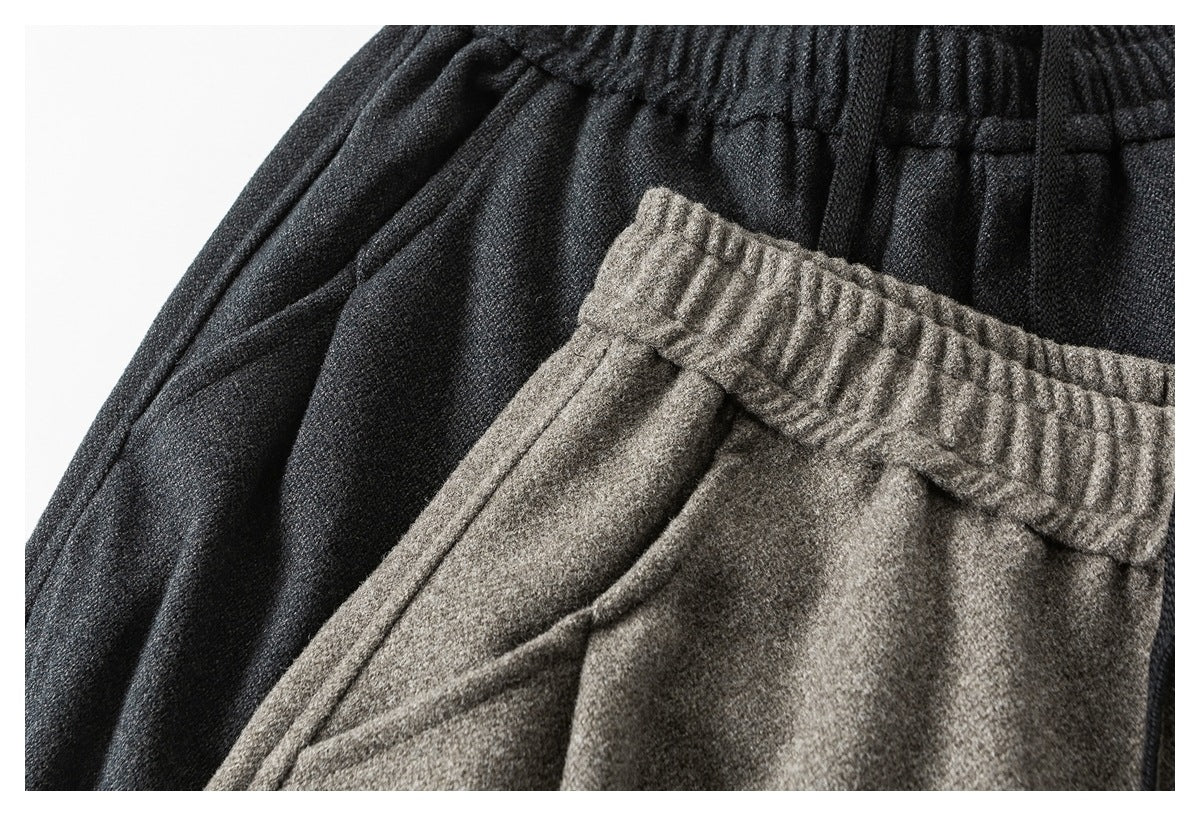 Close-up of gray and black pants layered together, showing the gathered waistbands and fabric texture.
