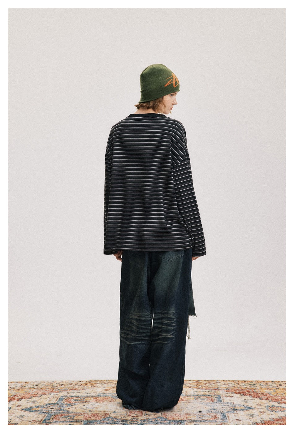 Model turned away to show the back of an oversized black shirt with fine gray stripes.