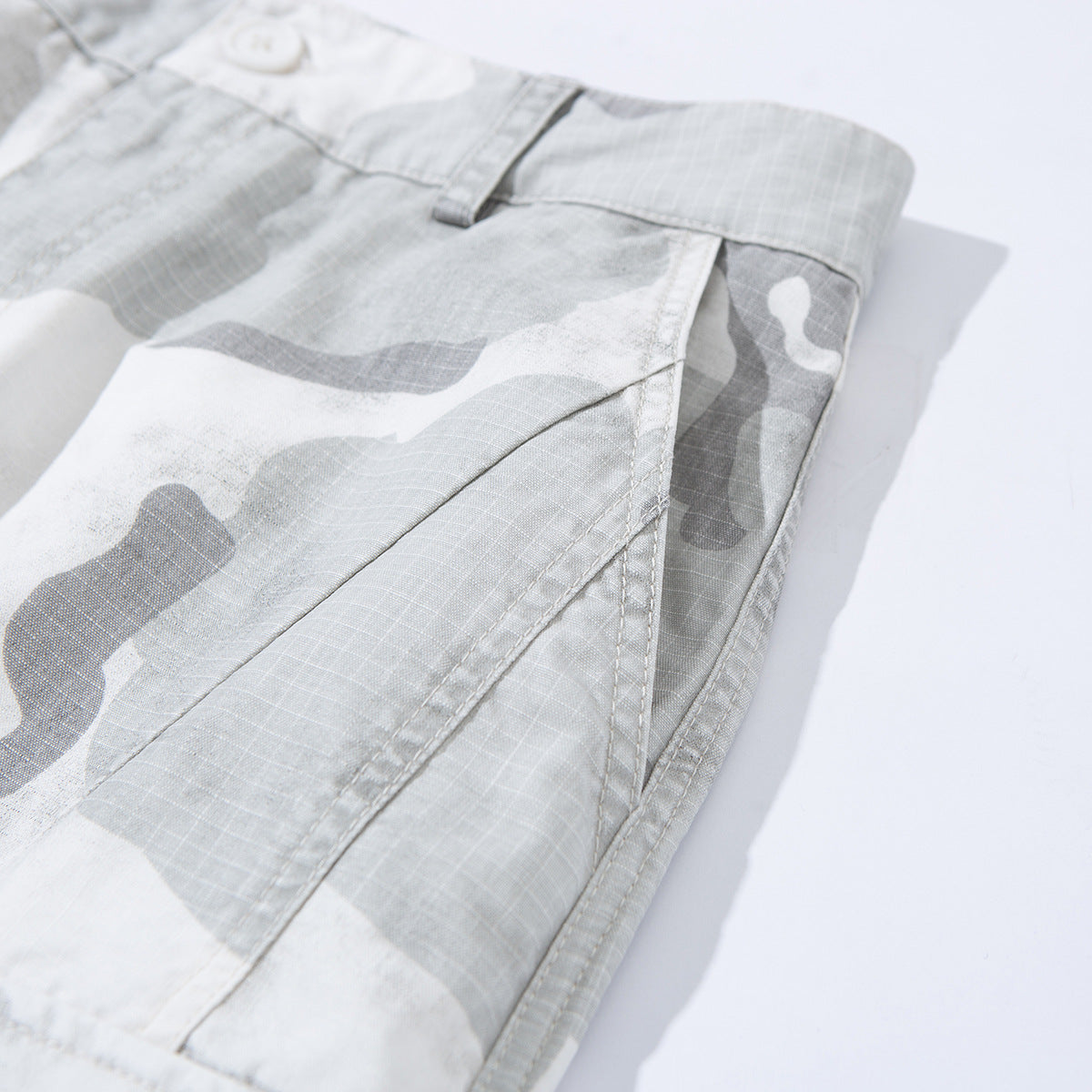 Close-up of gray and white camouflage shorts showing a belt loop, side seam, and pocket edge.