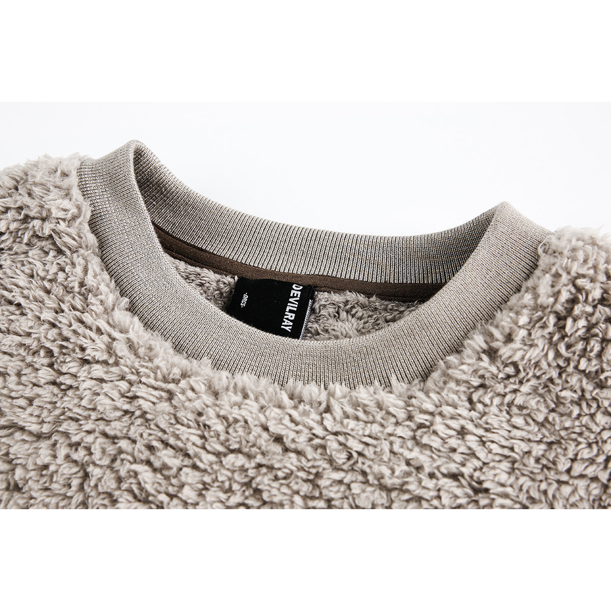 Close-up of a beige-gray plush sweatshirt neckline with ribbed trim and a black inner brand label.