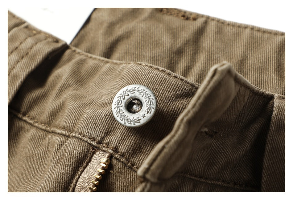 Close-up of the pants' engraved metal waist button and stitched waistband.