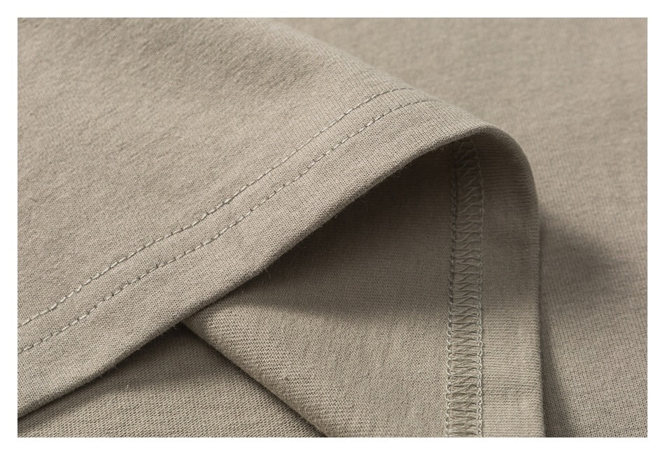 Close-up of a taupe garment's folded hem with visible stitching and interior overlock seam.