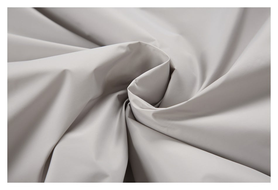 Close-up of smooth light gray fabric arranged in soft folds.