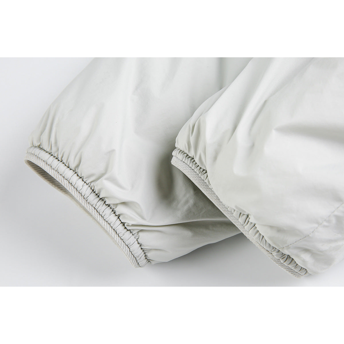 Close-up of a light gray jacket's elasticized sleeve cuffs and seams.