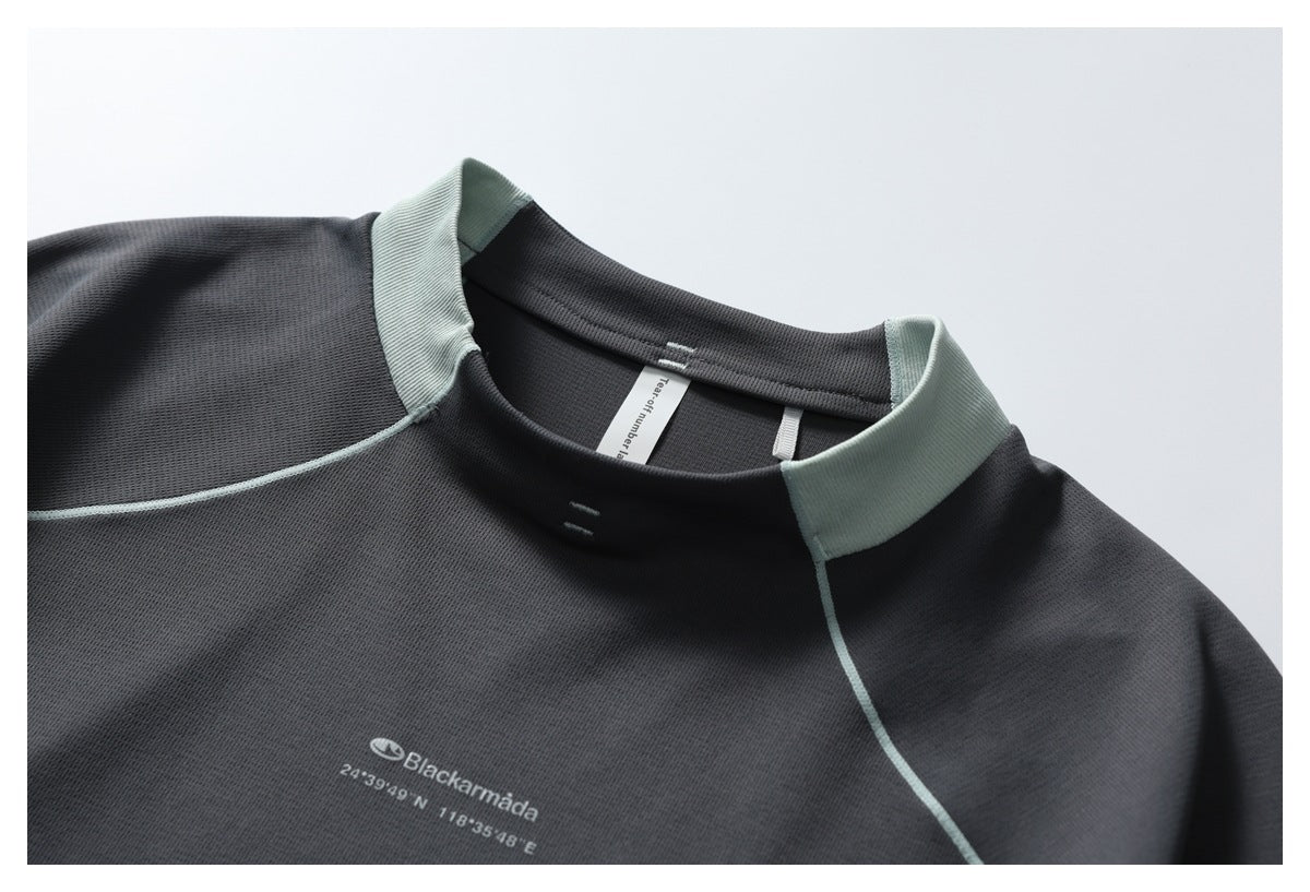 Close-up of the charcoal pullover's high collar, pale mint panels and chest print reading Blackarmada with coordinates.