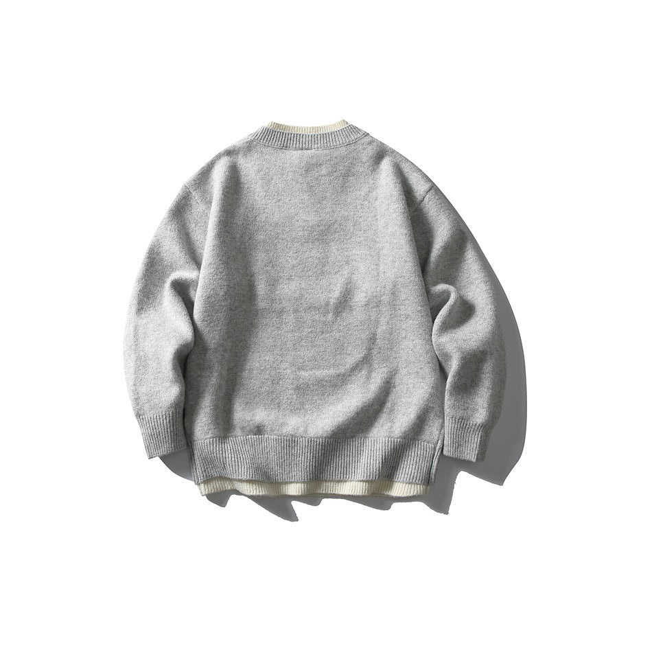 Back view of a light gray knit sweater with long sleeves and ribbed collar, cuffs, and hem; cream layer peeks below.