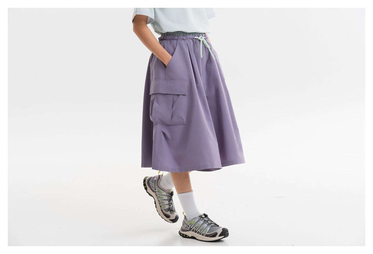 Close view of loose lavender cargo shorts with an elastic waist, mint drawstring, and large side pocket.