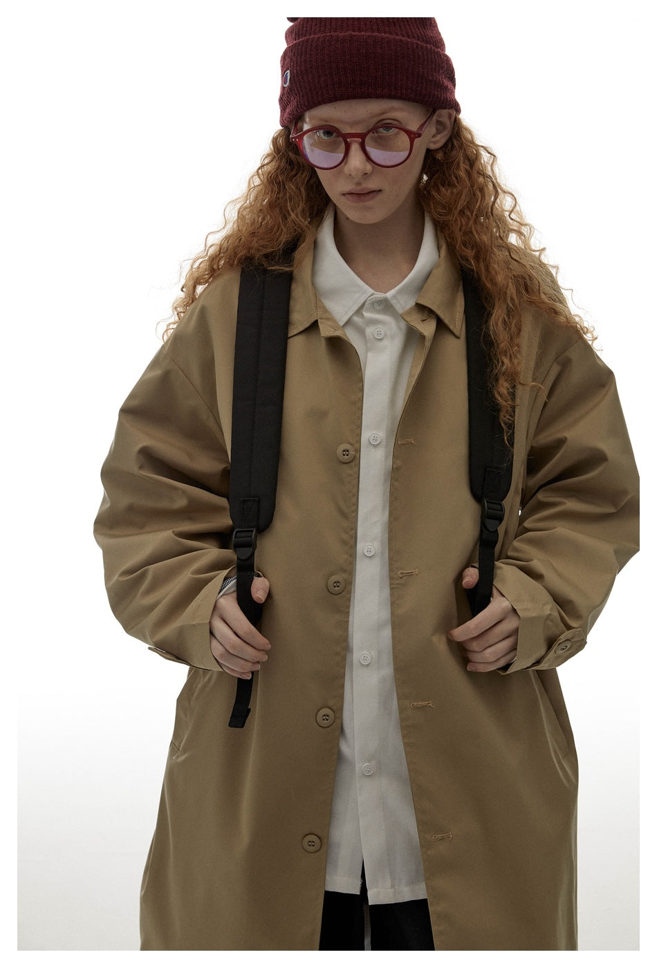 Close view of a model wearing the tan coat, showing its buttons, collar, and cuff tabs.