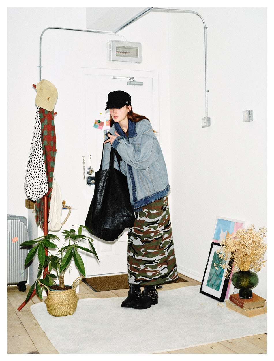 Model wearing an oversized light-wash denim jacket and long camouflage skirt, viewed from the front.