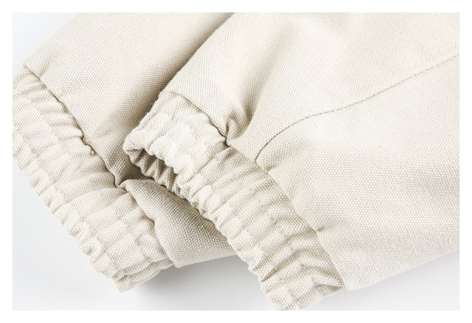 Close-up of gathered elastic edging and stitching on a cream garment.