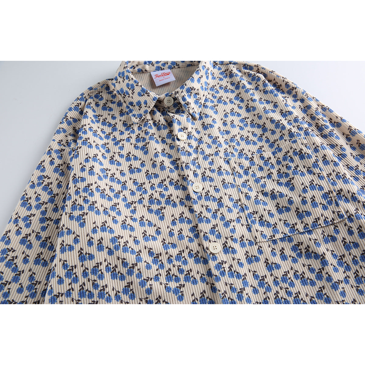 Front flat lay of a beige ribbed button-up shirt with a collar, chest pocket, and blue and dark floral print.