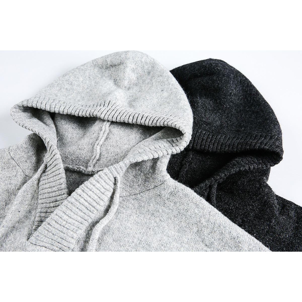 Close-up of light gray and charcoal hooded sweaters, showing their ribbed hood edges.