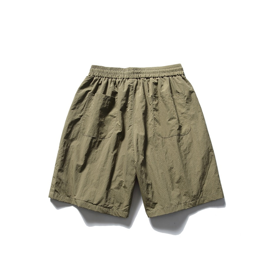 Olive-khaki shorts laid flat from the back, with an elastic waistband and two patch pockets.