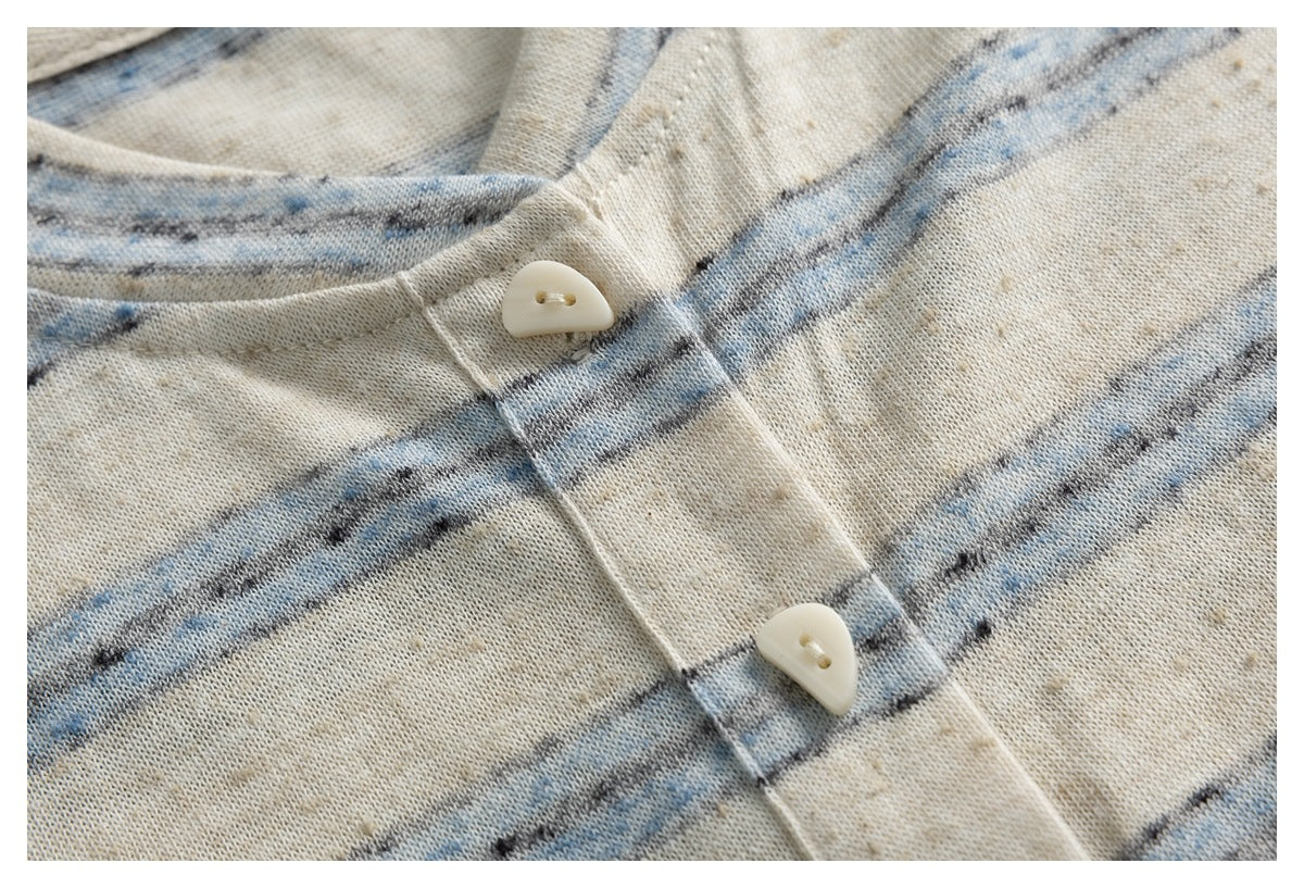 Close-up of two cream buttons on the front placket of a cream and blue striped top.