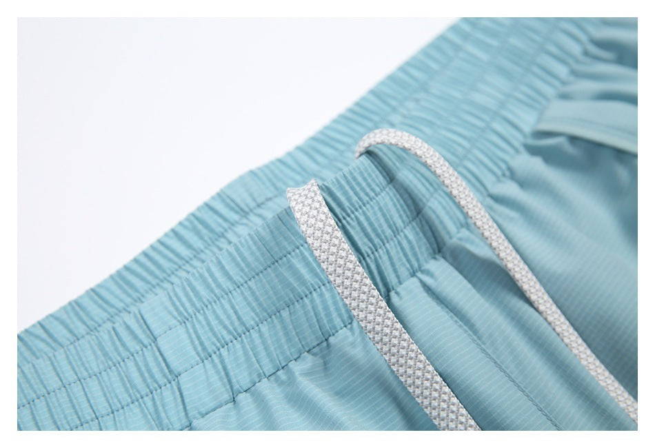 Close-up of a light blue striped elastic waistband with a white woven drawstring.