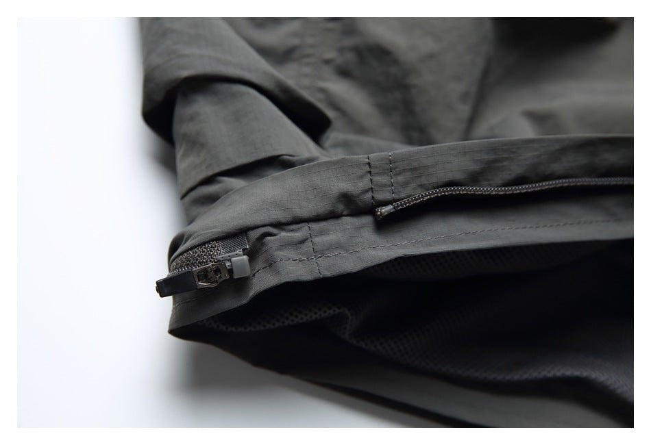 Close-up of a zippered opening at the hem of charcoal shorts.