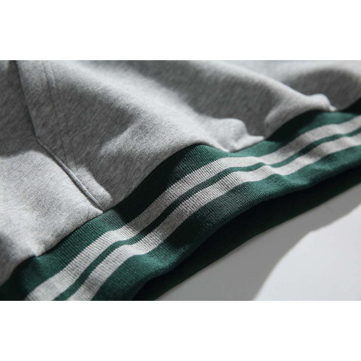 Close-up of gray hoodie fabric and green-and-gray striped ribbed hem.