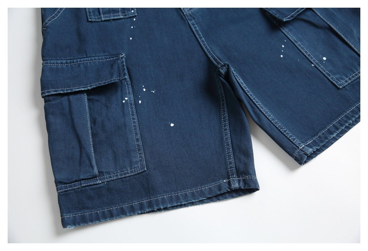 Close detail of dark blue denim shorts showing a large side cargo pocket, seams, hem, and white speckles.