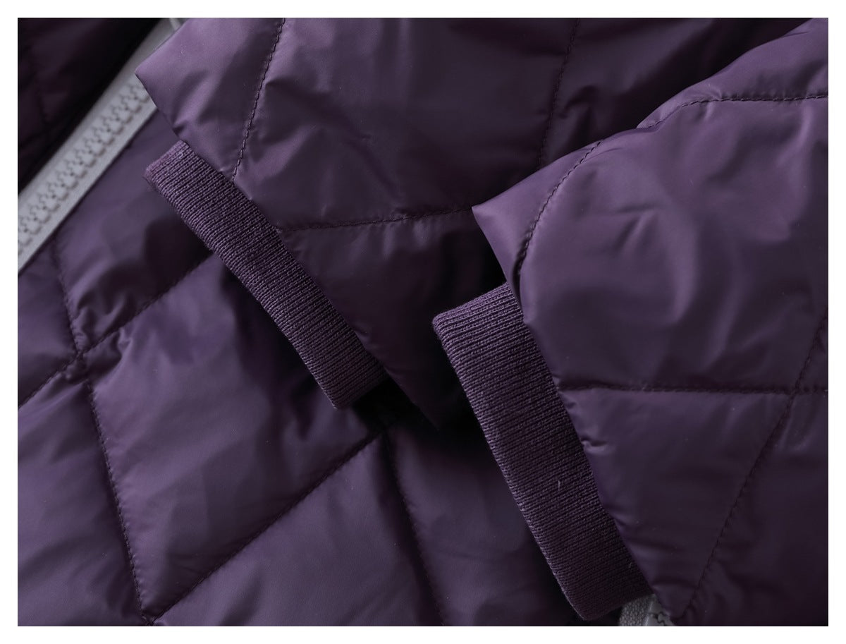 Close-up of two dark purple fabric fastening tabs against a quilted garment.