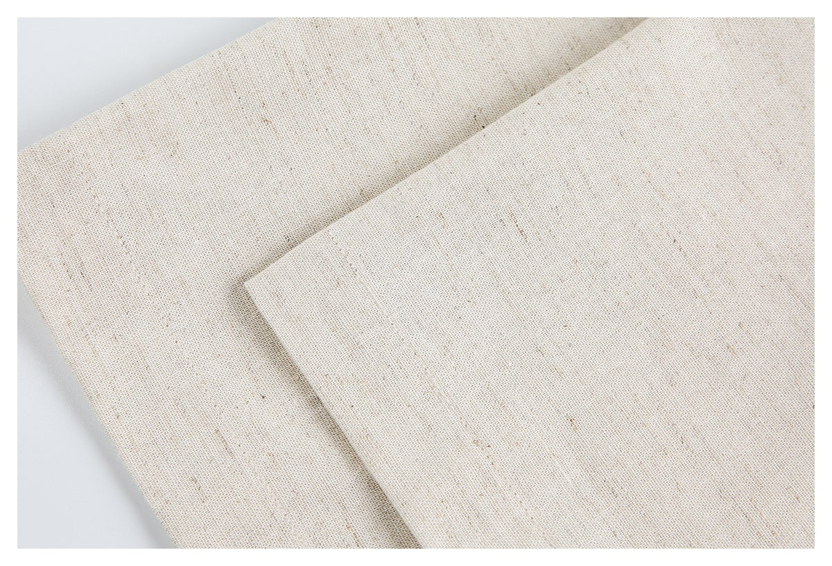 Close-up of folded and overlapping edges of ivory flecked garment fabric.