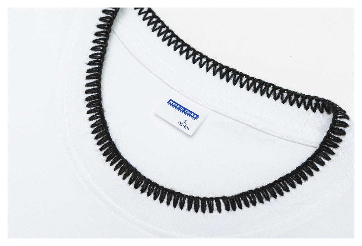 Close-up of a white garment neckline with thick black loop stitching and a small size and country-of-origin label.