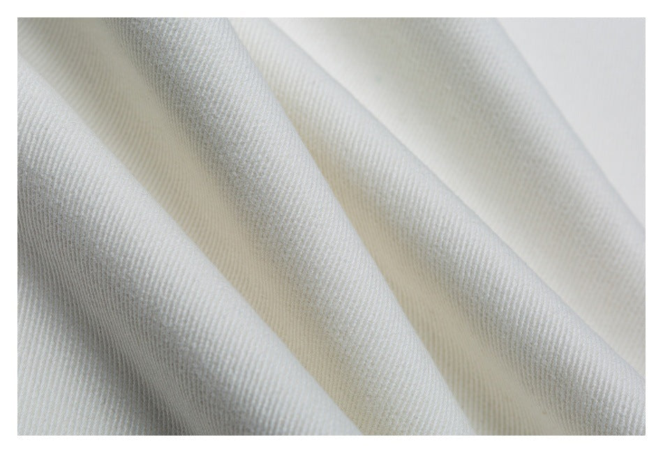 Close-up of folded white fabric showing its diagonal weave texture.