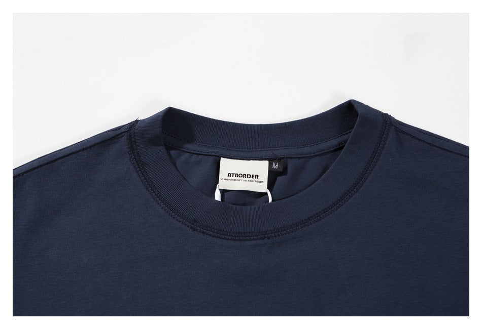 Close-up of the navy T-shirt’s ribbed crew neck and sewn-in brand and size labels.