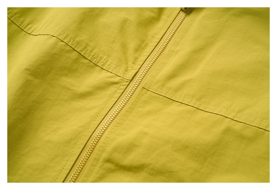 Close-up of a yellow-green garment showing a diagonal front zipper and stitched seams.