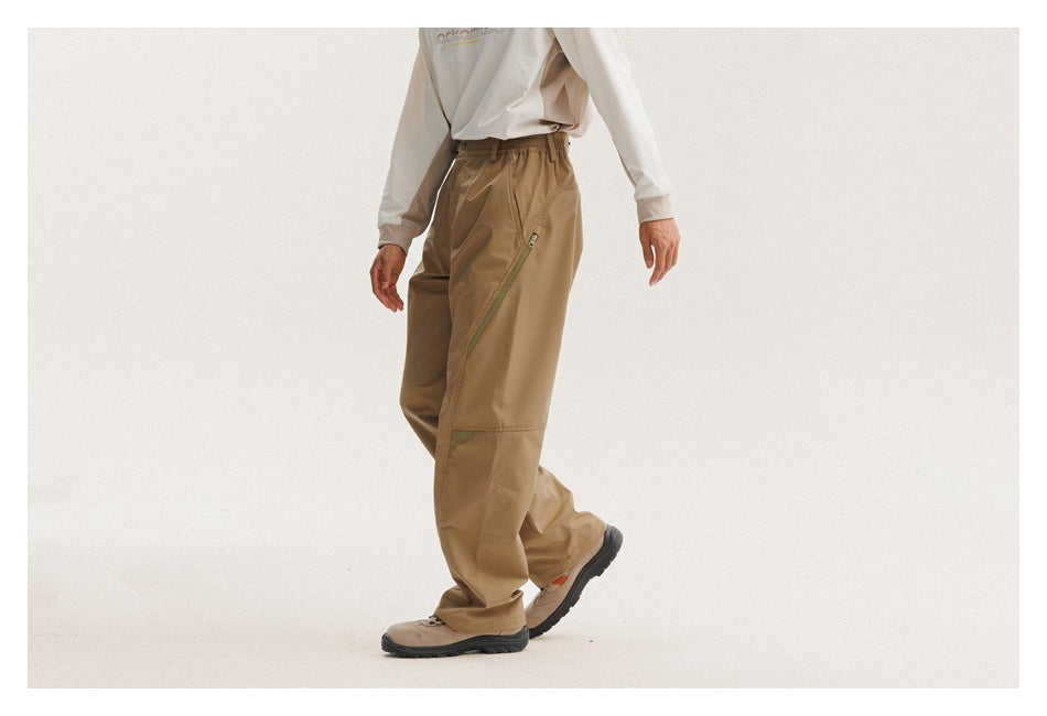 Side view of a person wearing tan outdoor pants with a diagonal zip pocket and reinforced knee panels.