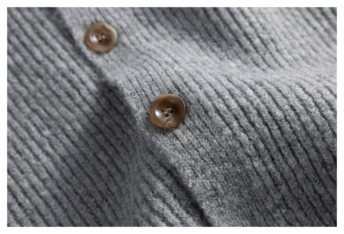 Close-up of the gray ribbed knit fabric and two brown buttons on a cardigan.