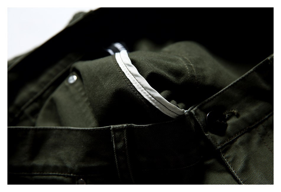 Close-up of a dark olive garment showing white trim, stitched seams, and dark buttons.