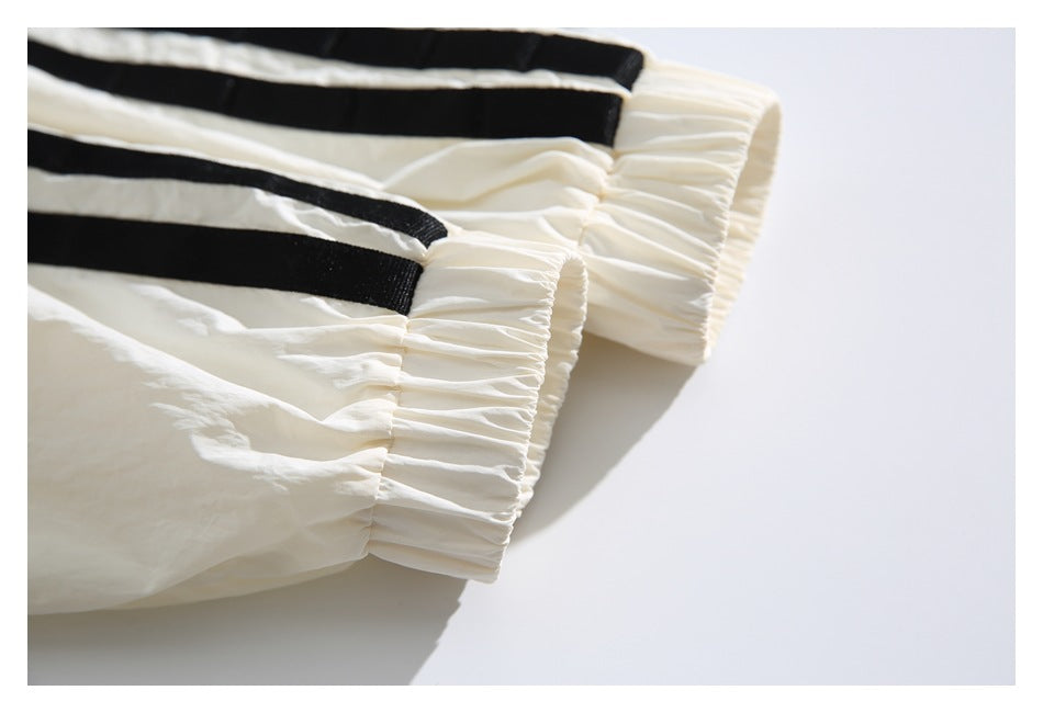 Close-up of gathered ivory elastic cuffs with black stripe trim.