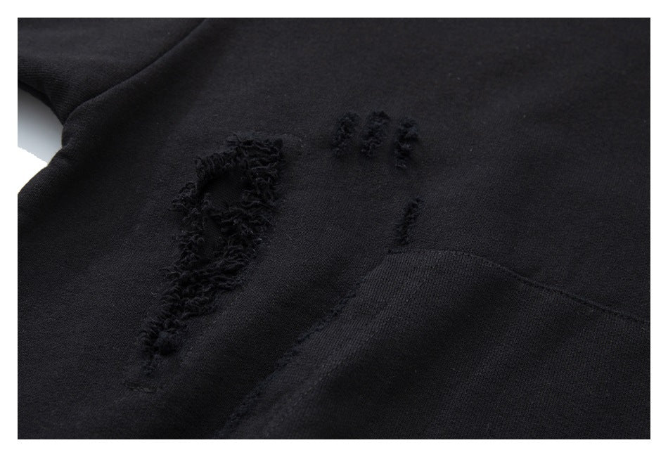 Close-up of a black hoodie showing distressed stitching beside its front pocket.
