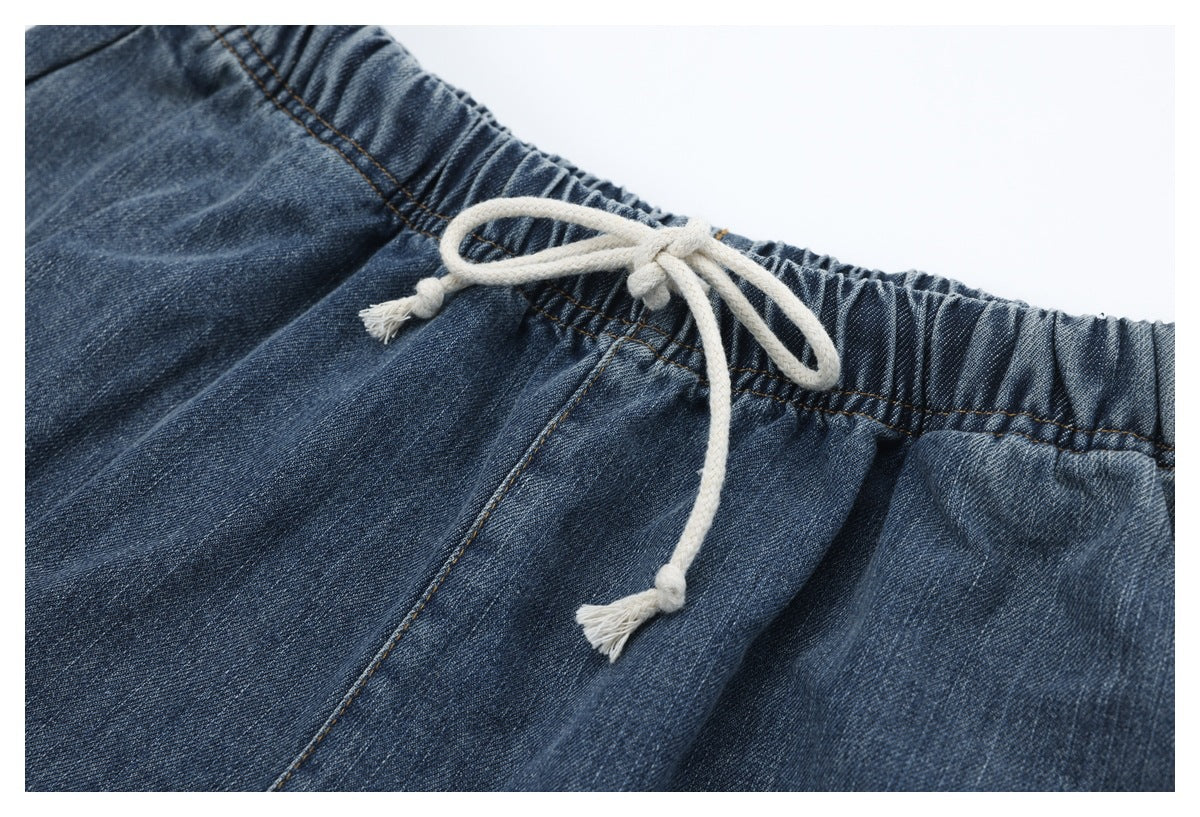 Close-up of blue denim trousers with an elastic waistband and tied white drawstring.