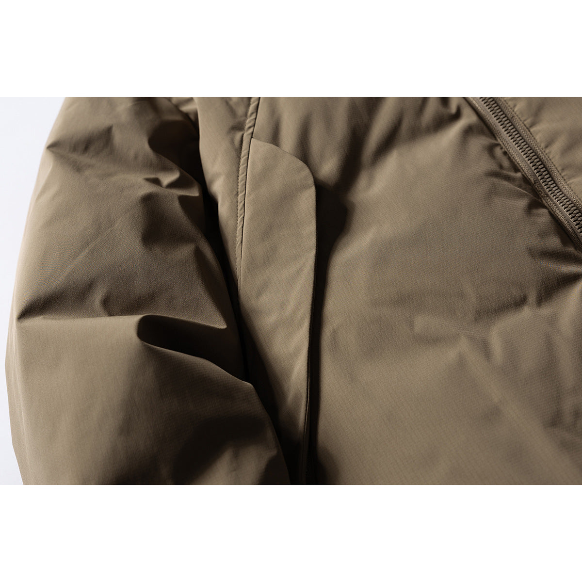 Close-up of an olive-brown jacket sleeve and front panel, with part of the zipper visible.