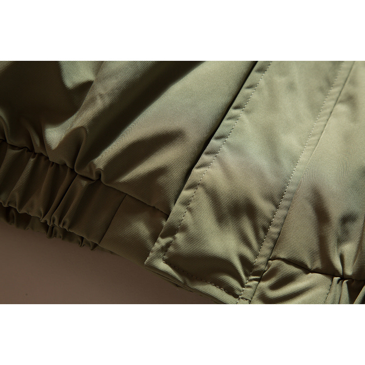 Close-up of the olive khaki jacket's gathered hem and stitched panel.