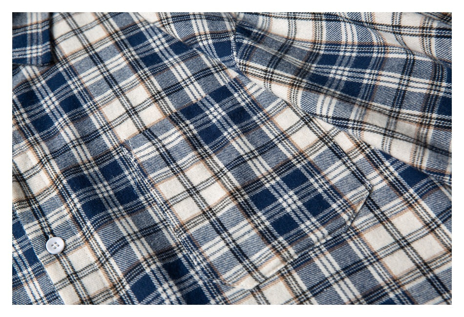 Close-up of a navy, cream, and tan plaid shirt showing a chest pocket and button.