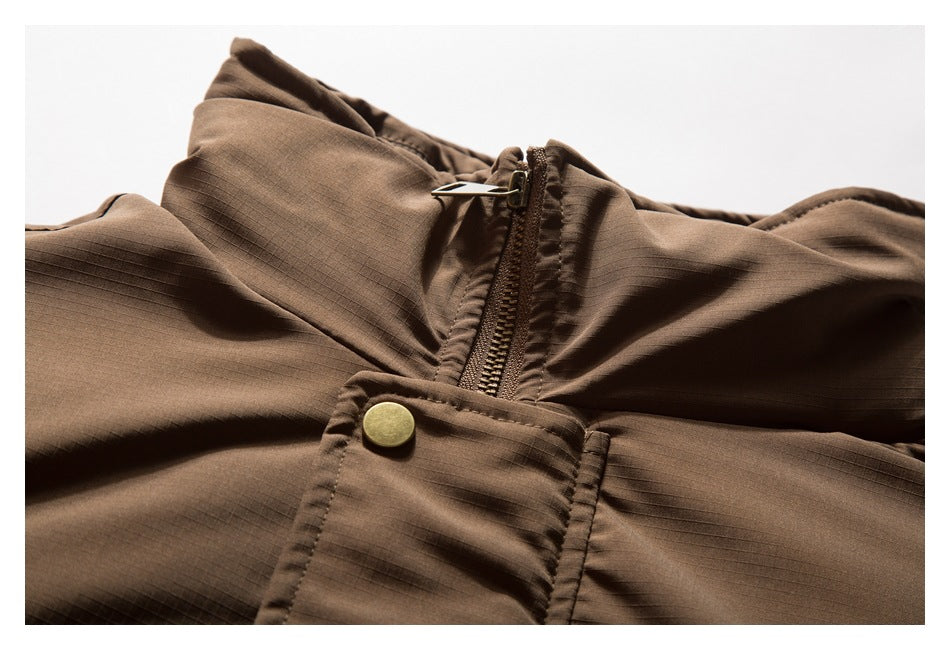 Close-up of a brown jacket collar, zipper, snap-button storm flap, and subtle grid texture.