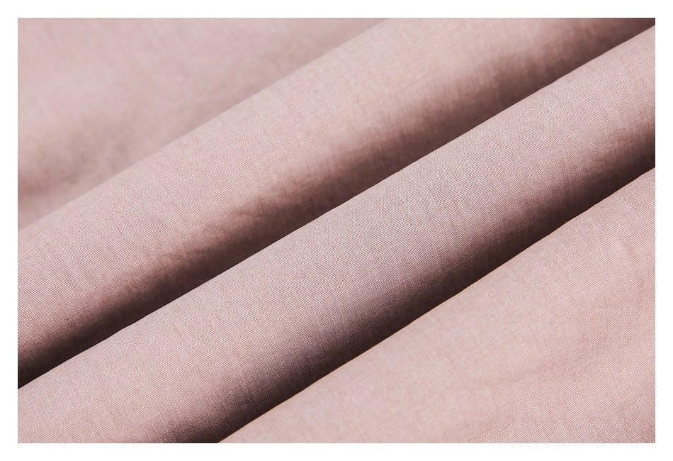 Close-up of dusty pink fabric arranged in soft folds, showing its fine woven texture.