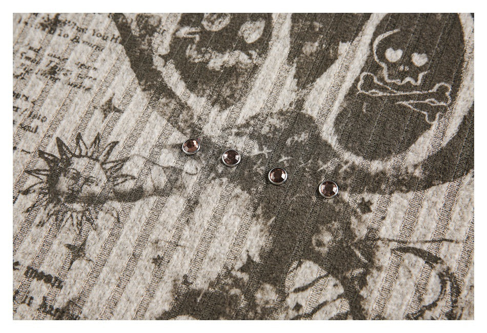 Close-up of a distressed skull and sun graphic with four metal studs on striped fabric.