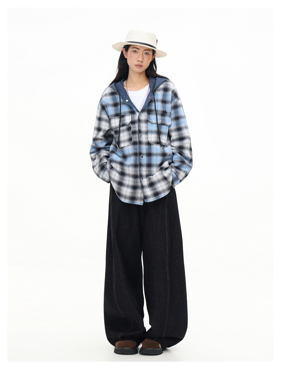 Full-length model wearing a blue-gray plaid hooded button-up shirt, black wide-leg pants, and a white hat.