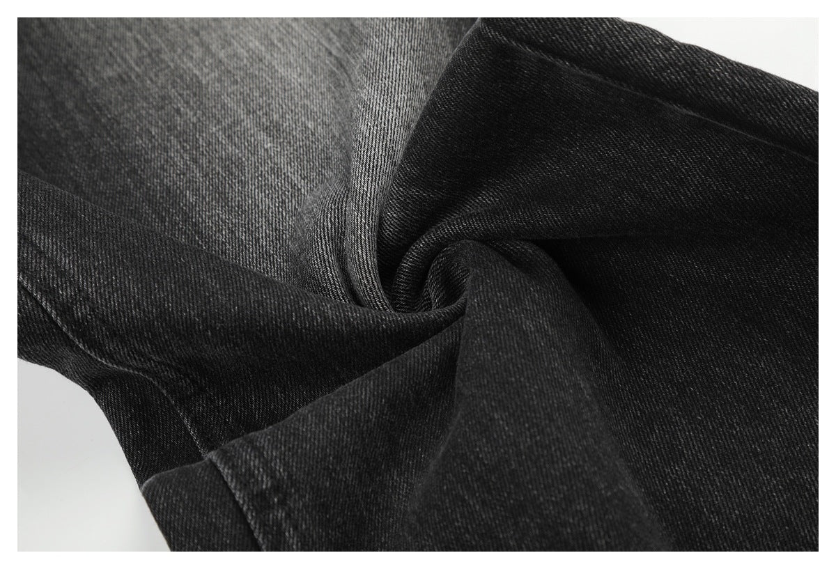 Close-up of charcoal-black denim gathered into folds, showing its twill texture and seams.