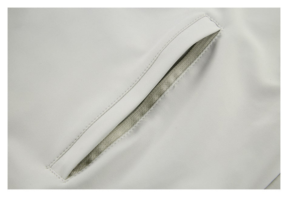 Close-up of a slanted welt pocket on light gray fabric, showing its opening and stitching.