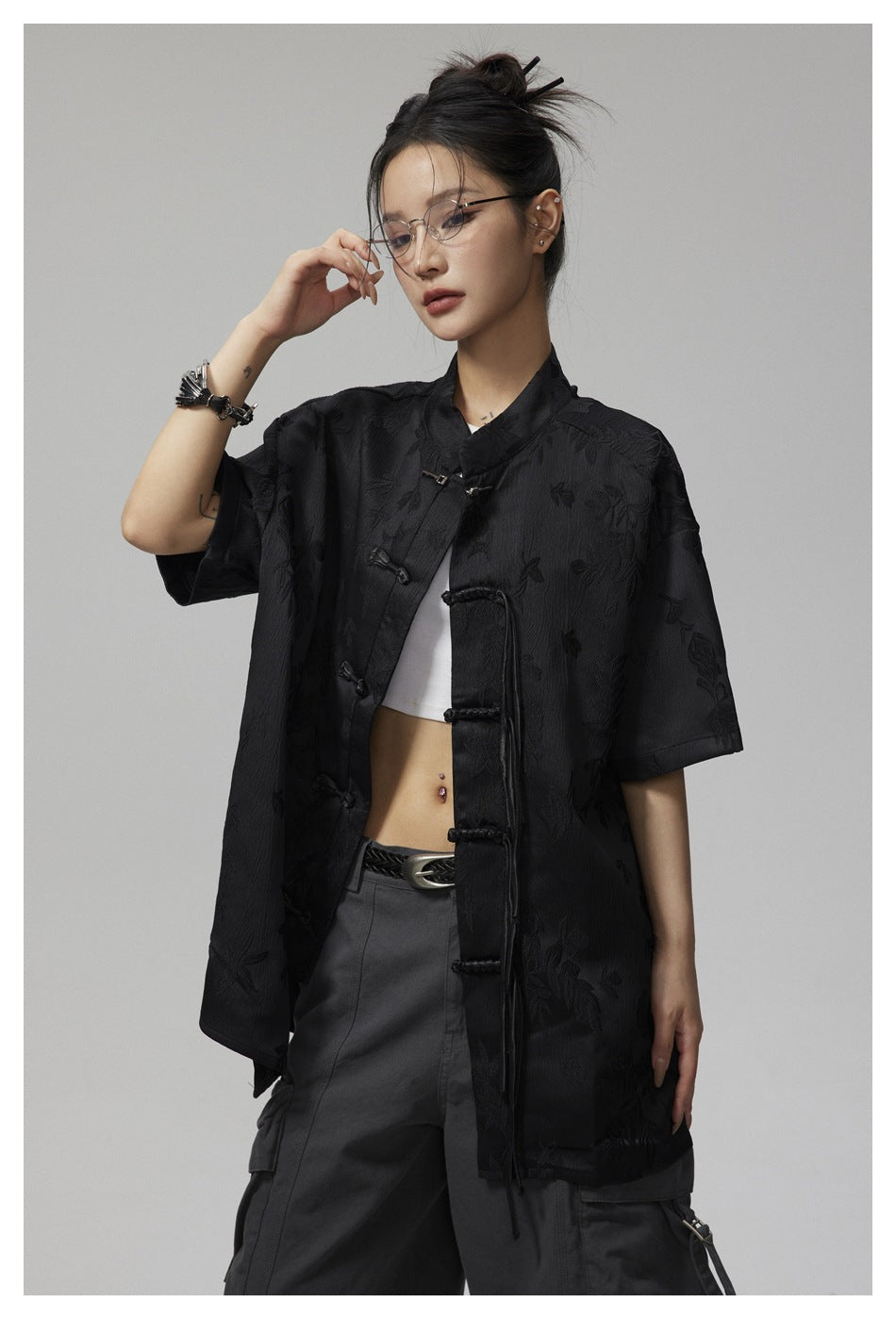 Model in a black short-sleeve floral jacquard shirt with frog closures, shown from a slight angle.
