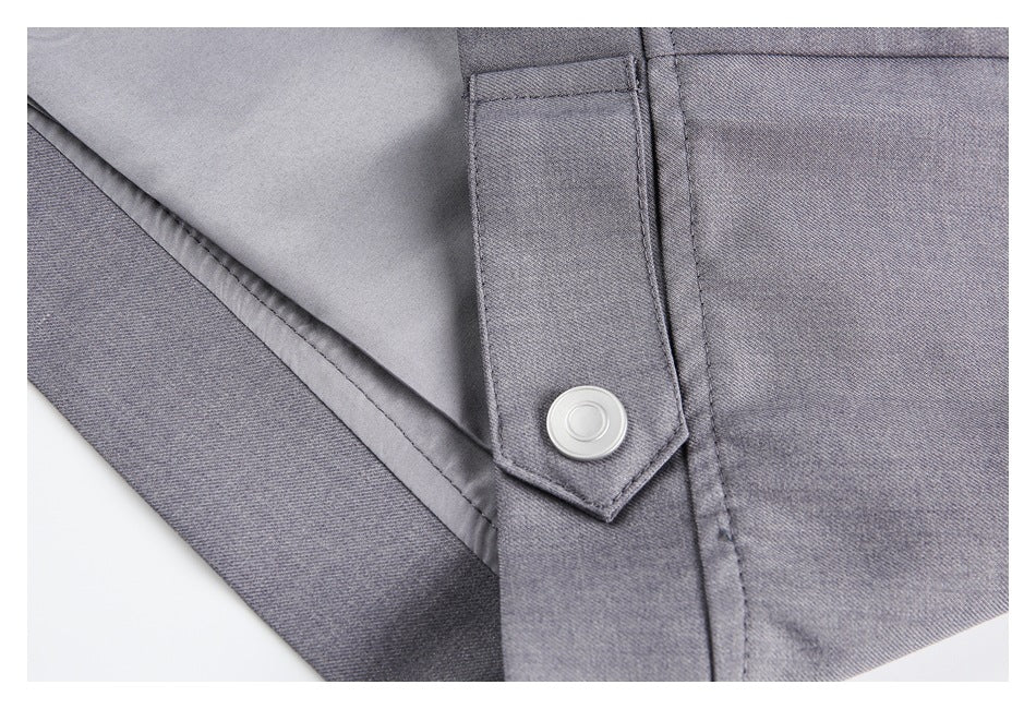 Close-up of a gray garment's fabric strap and round silver snap fastener.