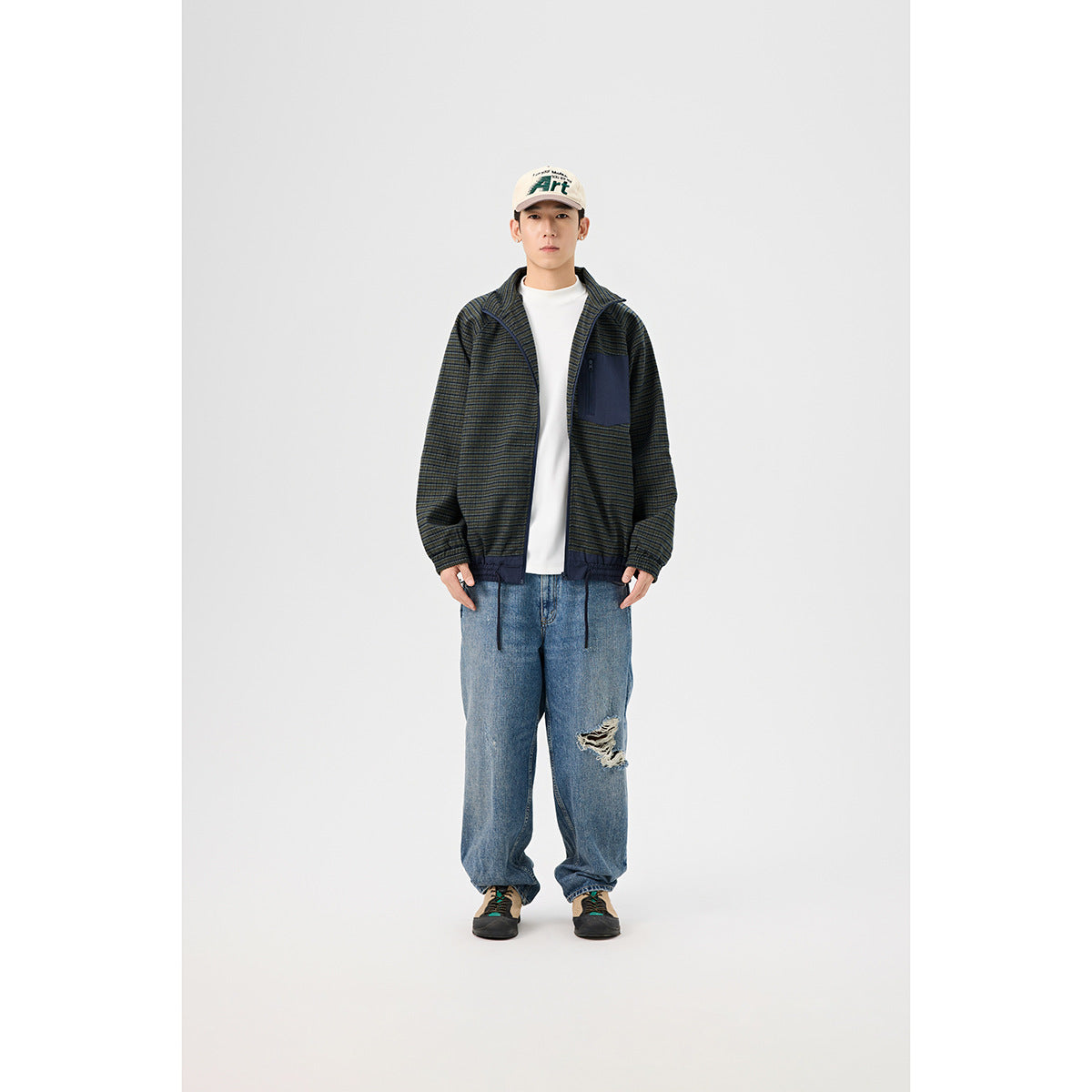 Front full-length view of a model in a dark striped zip jacket with a navy chest pocket and elastic hem.
